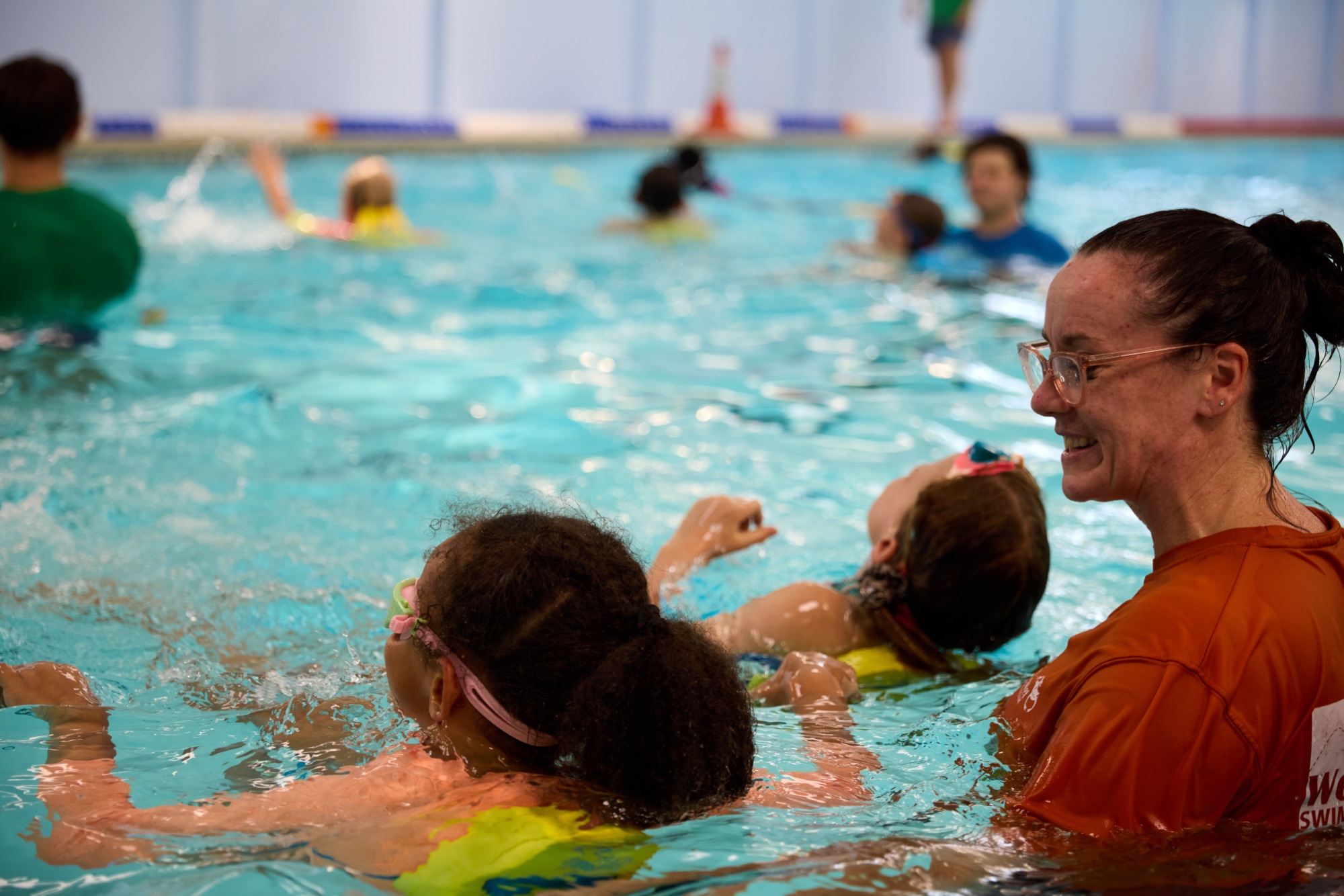 WetWetWet Swim School instructor smiling with two children learning to float